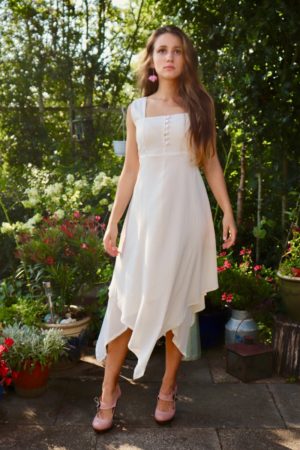 Elegant cream-colored dress with buttons at the chest. 2 thin layers in soft natural cotton and a trendy asymmetrical cutting.