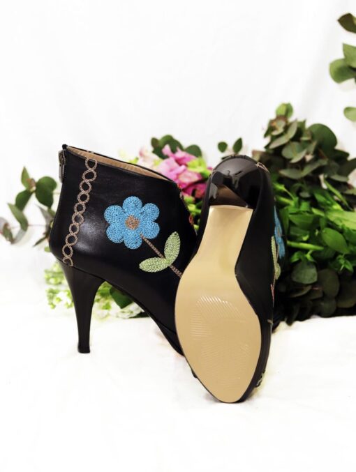 A pair of black handmade leather stilettos with bright colored flower embroidery