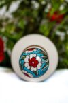 Handpainted floral lid on a handmade ceramic bottle with flowers