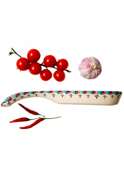 Spoon rest from the side in handmade ceramics with a border decorated with red, black and turquoise motifs