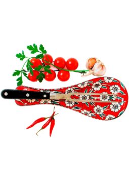 Flot keramisk skeholder i rød med hvide blomstermotiver, til at lægge bestik og køkkenredskaber på under madlavningen.