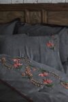 Handmade floral embroideries in red, rose and green colors decorating elegant anthracite grey bed linen in organic cotton satin .